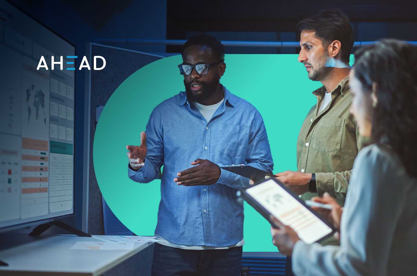 three coworkers standing in front of a computer monitor